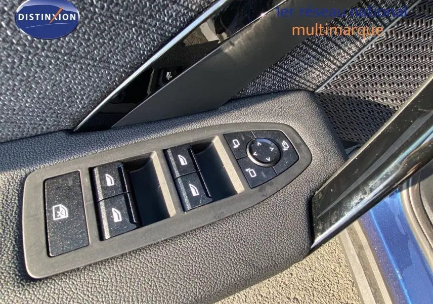 Gros plan sur les commandes des vitres et rétroviseurs côté gauche d'un BMW X1 bleu phytonic metal 2024.