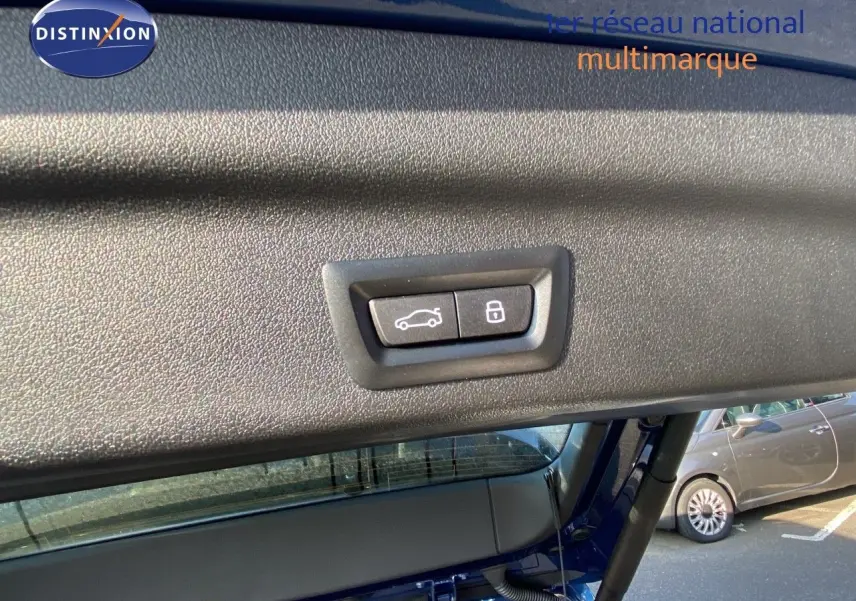 Boutons de fermeture et verrouillage du hayon sur le coffre d'un BMW X1 bleu phytonic metal, vue intérieure arrière.