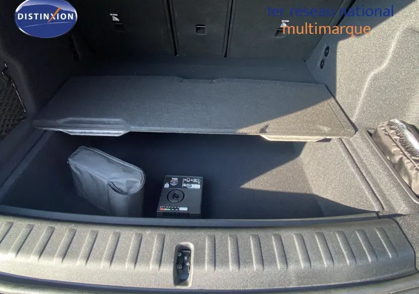 Coffre ouvert du BMW X1 18I bleu Phytonic Metal, montrant le rangement sous plancher avec kit de réparation pneus.