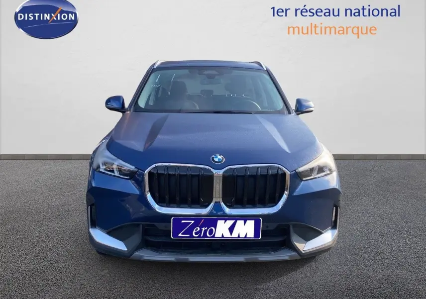 BMW X1 18I 136CH bleu Phytonic Metal vue de face avec calandre imposante et phares LED allumés