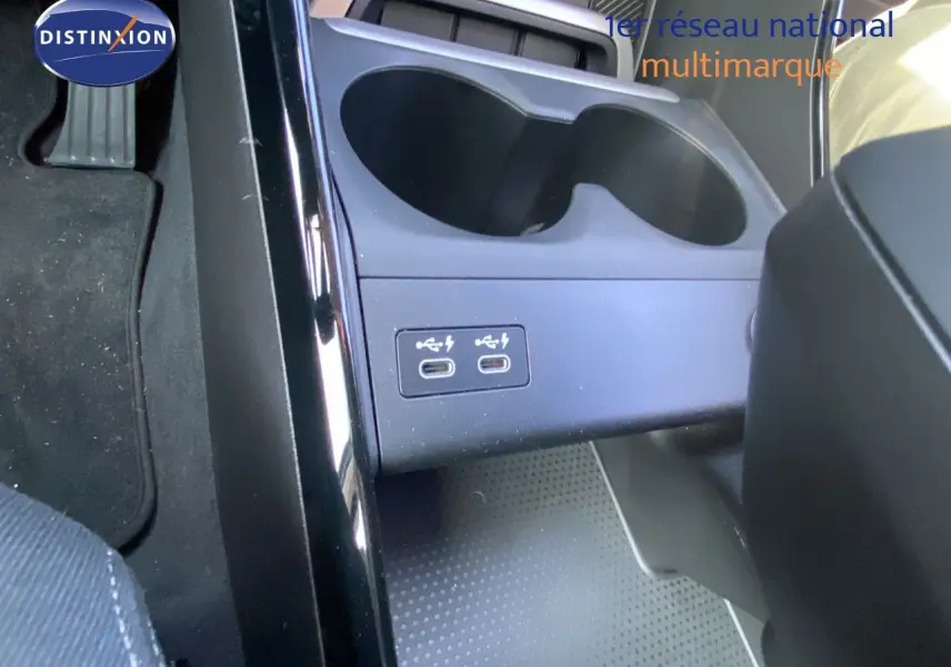 Gros plan sur la console centrale du BMW X1 18I bleu Phytonic, montrant deux ports USB-C et porte-gobelets.