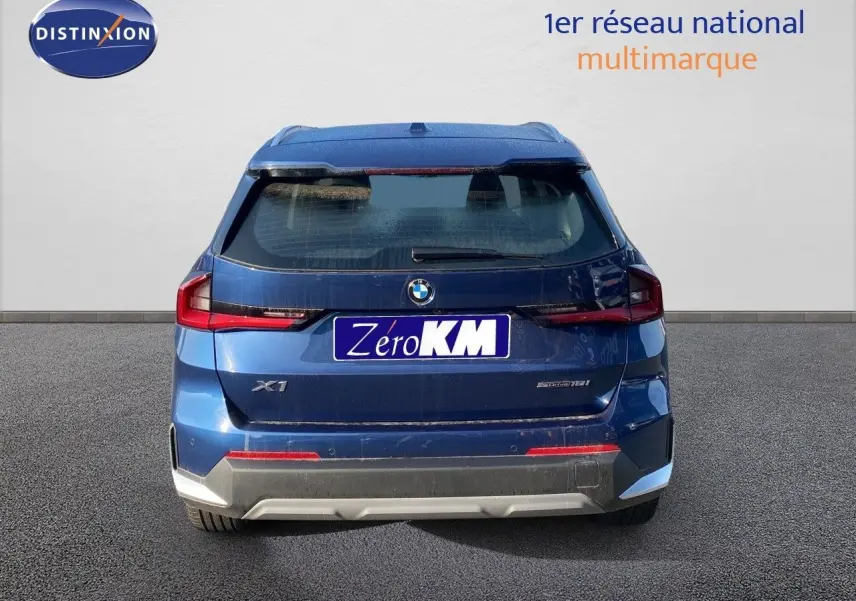 Vue arrière d'un BMW X1 18I bleu Phytonic Metal avec feux LED et plaque Zéro KM visible.