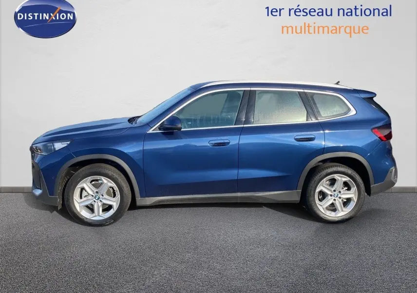 BMW X1 18I 136CH bleu Phytonic Metal vu de profil côté gauche, avec jantes alliage et lignes épurées.