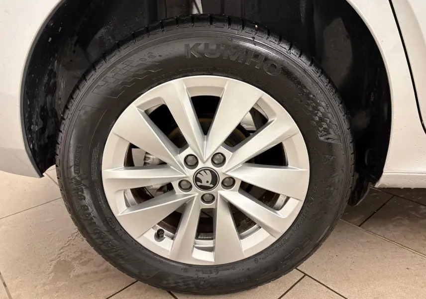 Gros plan sur la roue avant droite du Skoda Kamiq gris argent avec jante alliage et logo central visible.