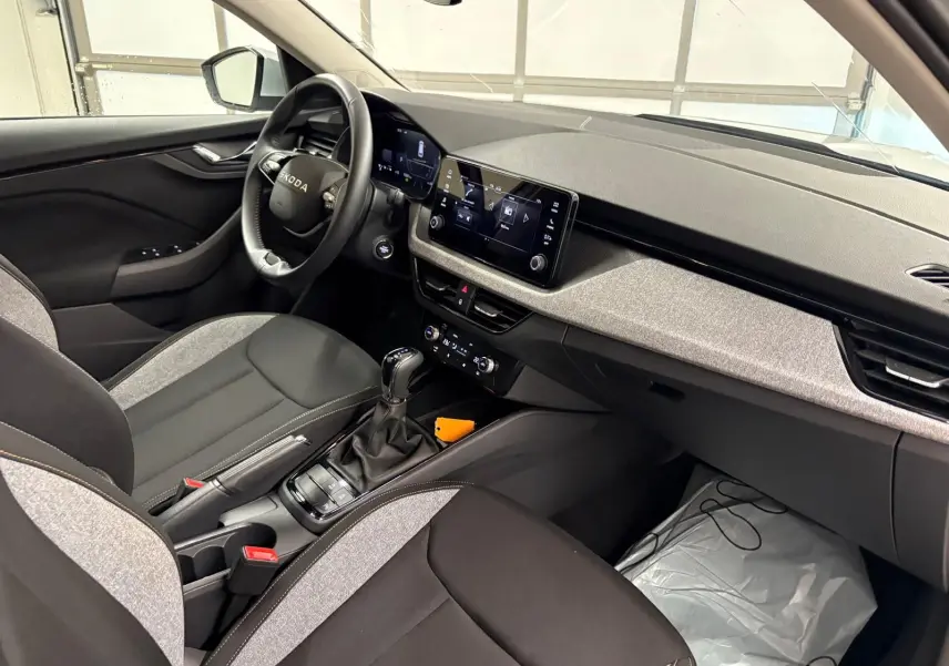Vue intérieure côté conducteur du Skoda Kamiq 2025, mettant en valeur la console centrale avec boîte auto et écran tactile.