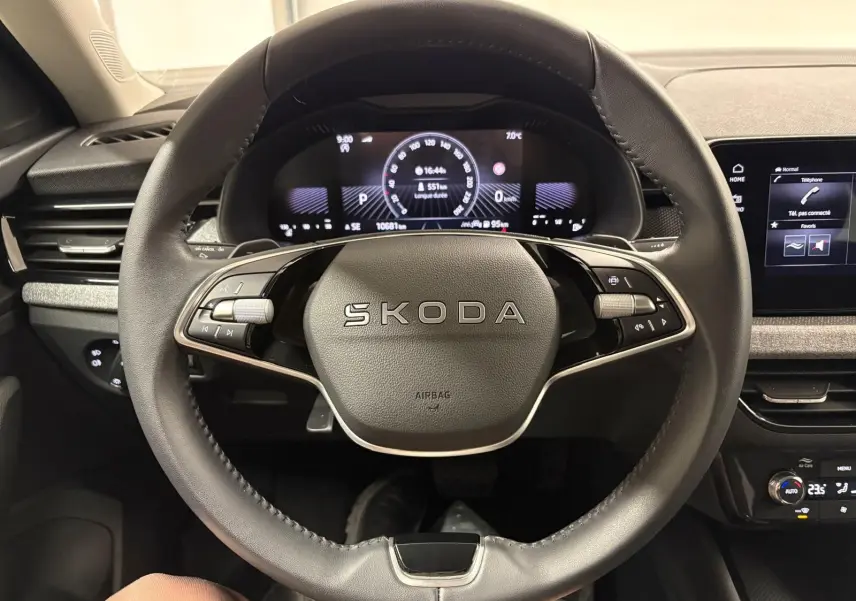 Vue intérieure centrée sur le volant SKODA du KAMIQ 2025 avec tableau de bord numérique et commandes intégrées.