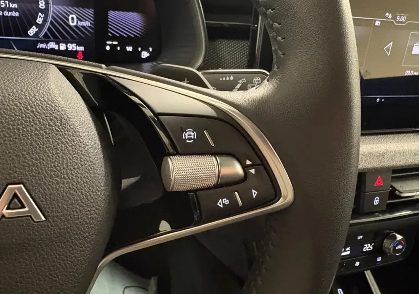 Gros plan sur le volant côté gauche du Skoda Kamiq gris argent 2025 avec commandes intégrées et tableau de bord numérique.