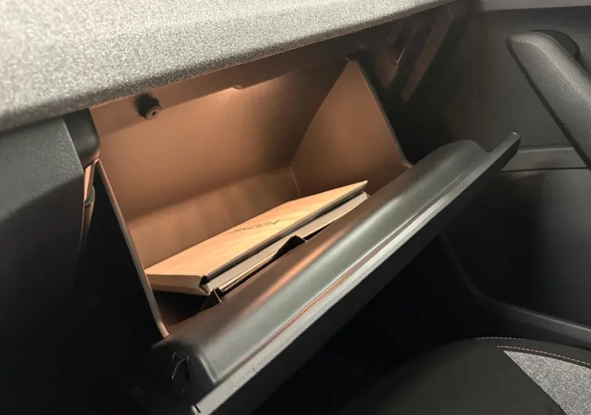 Gant de boîte à gants ouvert dans l'habitacle du Skoda Kamiq 2025, avec manuel visible à l'intérieur.