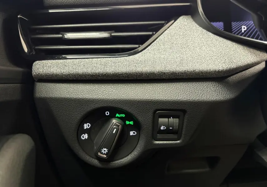 Gros plan sur le bouton de commande des phares du Skoda Kamiq gris argent, avec réglage automatique activé.