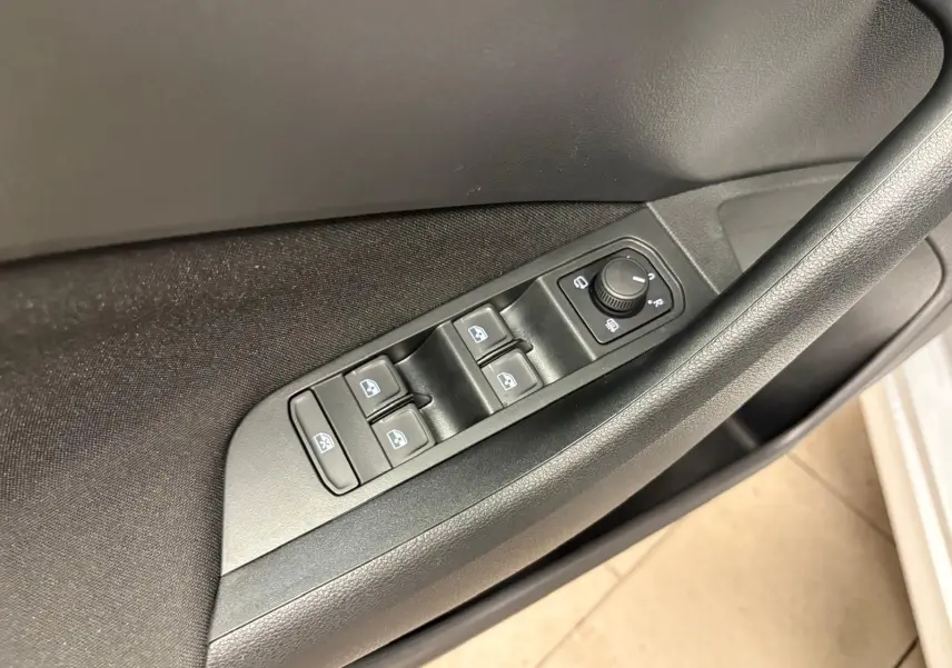 Gros plan sur les commandes des vitres et des rétroviseurs côté conducteur d’un Skoda Kamiq gris argent 2025.