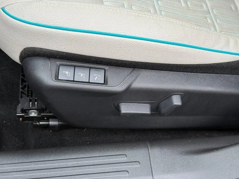 Détail des commandes de réglage électrique du siège avant avec cuir noir et surpiqûres bleues sur Fiat 600 2024.