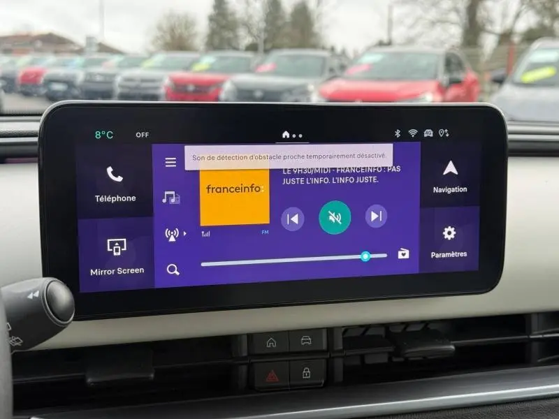 Écran tactile central du tableau de bord de la FIAT 600 noire, affichant l'interface multimédia avec radio et navigation.