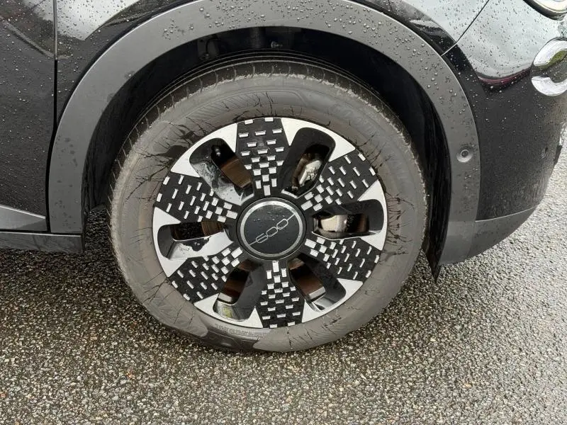 Gros plan sur la roue avant gauche noire d'une FIAT 600 2024 avec jante alu au design moderne et logo central 500.