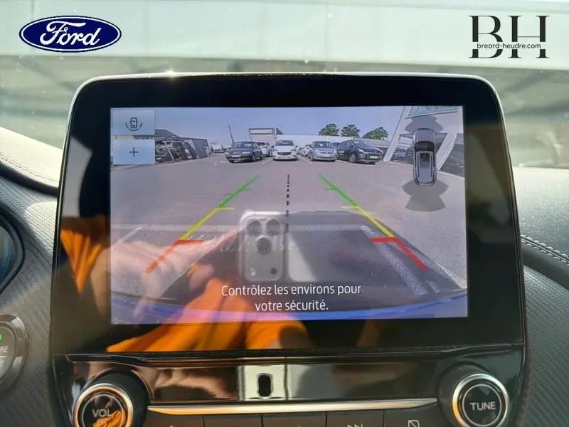 Écran tactile intérieur montrant la caméra de recul du Ford Puma bleu Fashion Island avec aides au stationnement visibles.