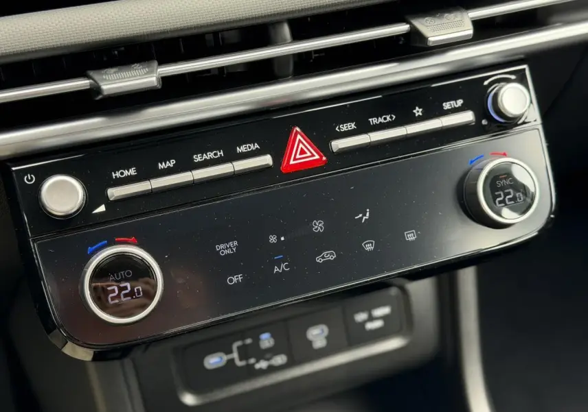 Vue rapprochée de la console centrale du Hyundai Tucson 2026, avec commandes de climatisation digitale et boutons multifonctions noirs.