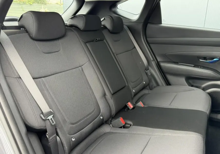 Vue intérieure côté droit des sièges arrière gris foncé du Hyundai Tucson 2026 avec ceintures et appuie-têtes visibles.