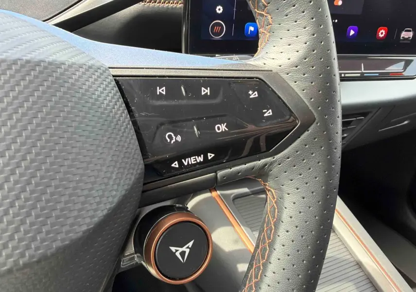 Gros plan sur le volant perforé noir avec surpiqûres cuivre du CUPRA Born 2024 et commandes multifonctions côté gauche.