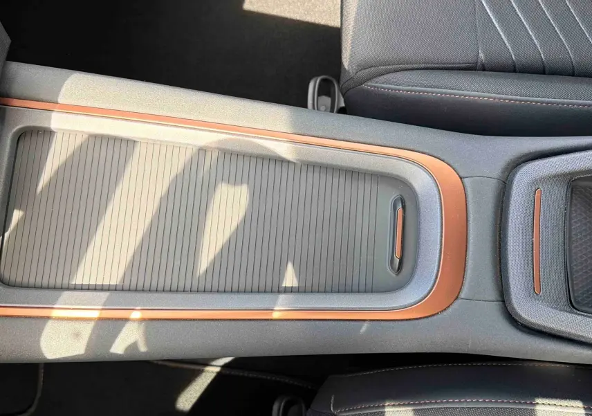 Vue plongeante sur la console centrale du CUPRA Born blanc, avec insertions cuivre et rangement coulissant fermé.