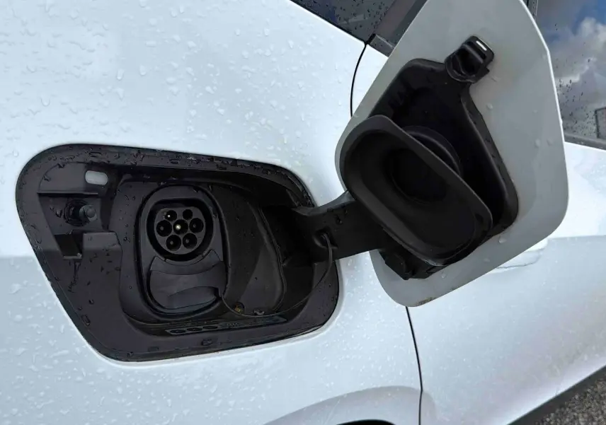 Prise de recharge électrique ouverte sur le côté gauche d'une CUPRA Born blanche sous la pluie.