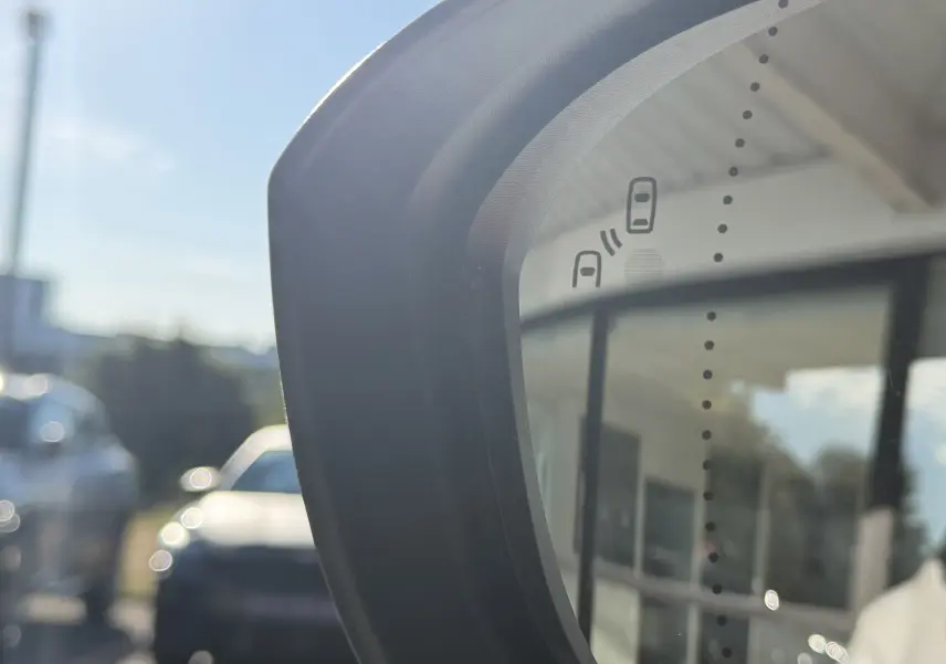 Gros plan sur le rétroviseur droit du Renault Austral blanc nacré, affichant l'alerte d'angle mort.