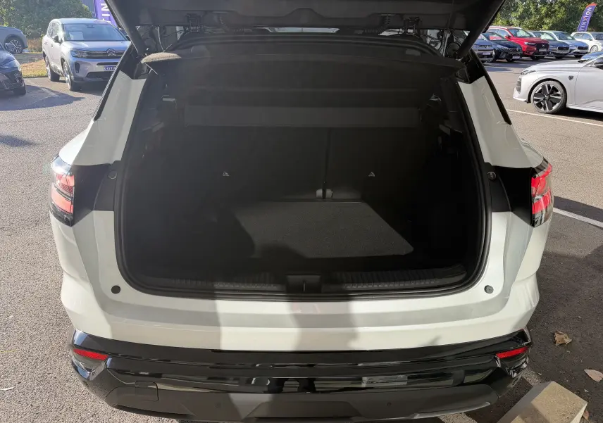 Vue arrière du coffre ouvert du Renault Austral E-Tech 200 Esprit Alpine blanc nacré avec toit noir, en extérieur.