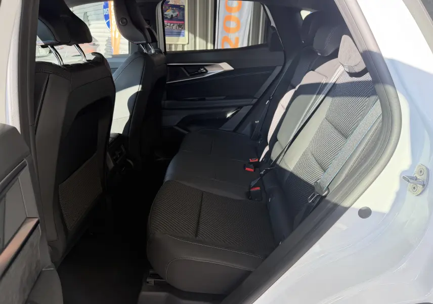 Vue latérale droite de l’intérieur arrière du Renault Austral E-Tech 200 Esprit Alpine, sièges noirs avec surpiqûres bleues.