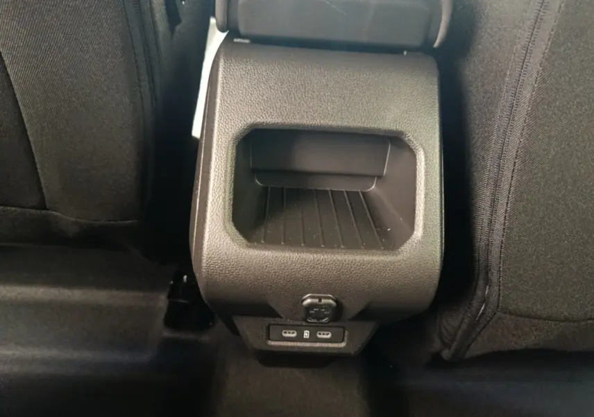 Vue rapprochée de la console arrière noire du Dacia Duster Journey Hybrid 155 avec ports USB et prise 12V.
