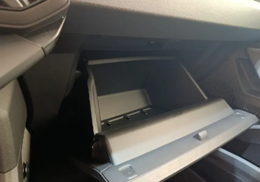 Vue rapprochée de la boîte à gants ouverte côté passager dans l’habitacle noir du Dacia Duster Journey Hybrid 2026.