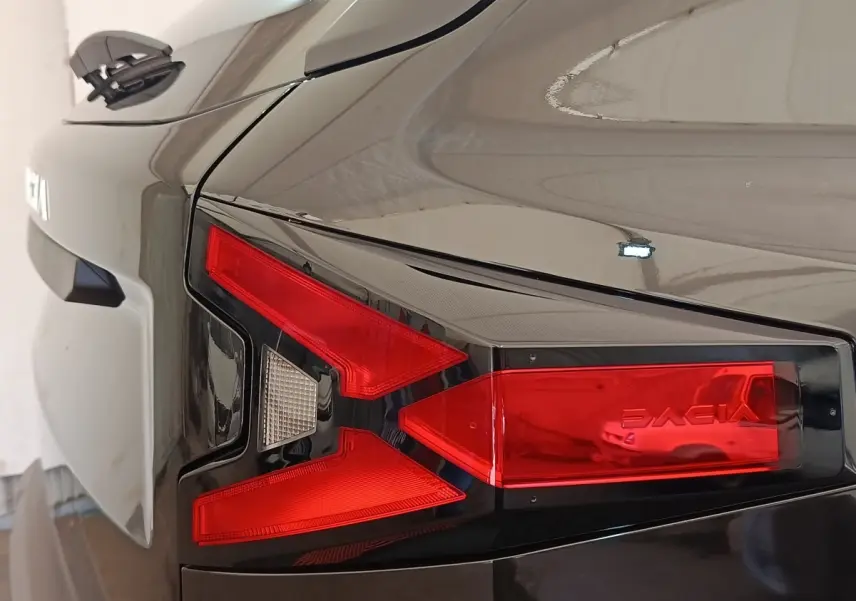Gros plan sur le feu arrière droit rouge et blanc d'un Dacia Duster Journey Hybrid 155 noir, finition 2026.