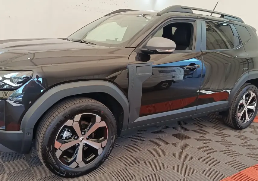 Vue de profil côté gauche du Dacia Duster Journey Hybrid 155 noir, avec jantes alliage et barres de toit noires.