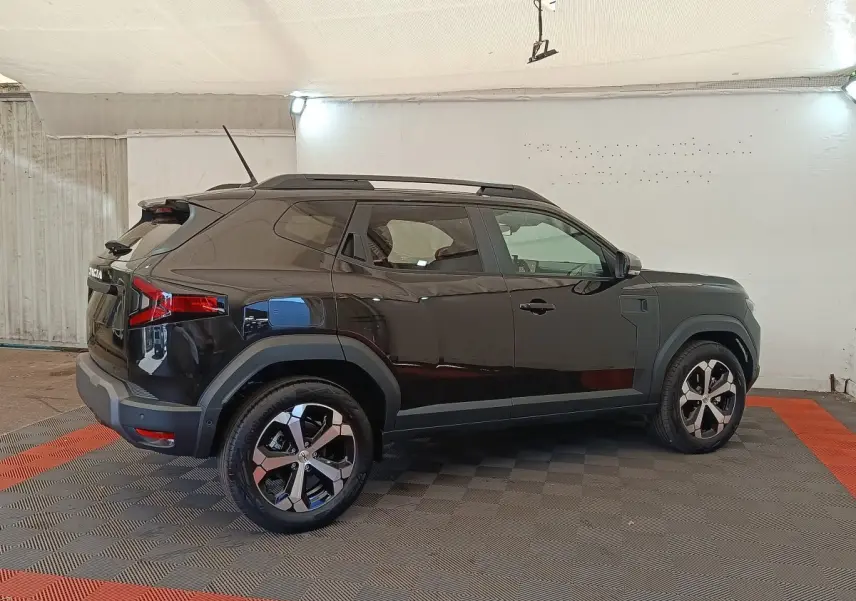Vue de profil côté gauche d'un Dacia Duster Journey Hybrid 155 noir, avec jantes alliage et barres de toit noires.