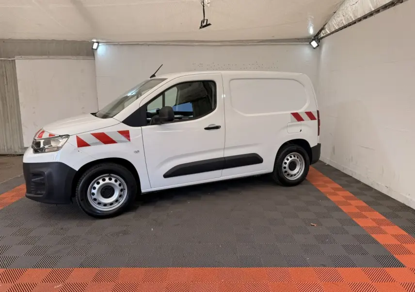 Vue de profil côté gauche d’un Citroën Berlingo blanc 2019 avec bandes rouges diagonales sur l’aile avant et l’arrière.