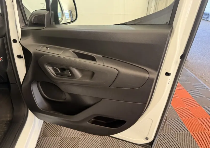 Vue rapprochée de la porte avant gauche blanche d’un Citroën Berlingo 2019, intérieur noir avec poignée et commande de vitre.