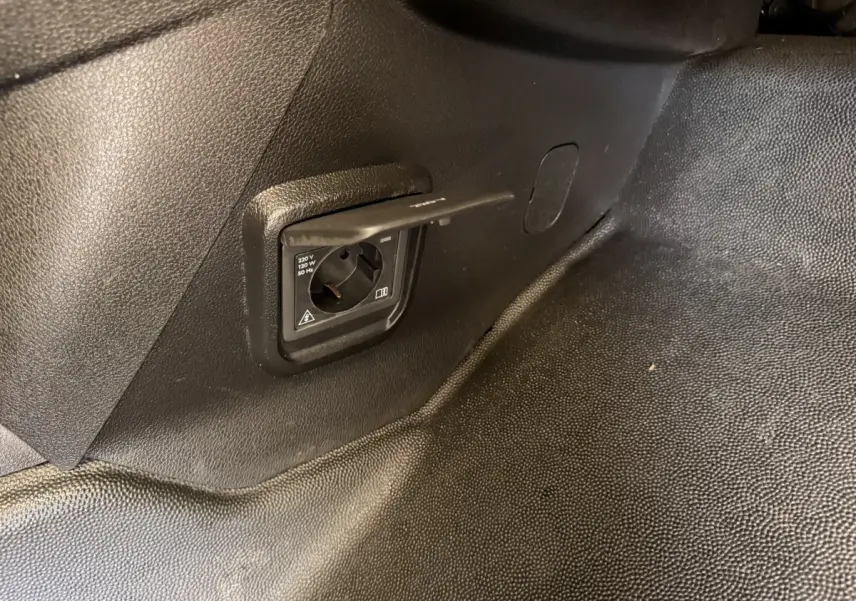 Prise électrique 220V intégrée dans l’espace de chargement du Citroën Berlingo blanc de 2019, vue intérieure côté droit.
