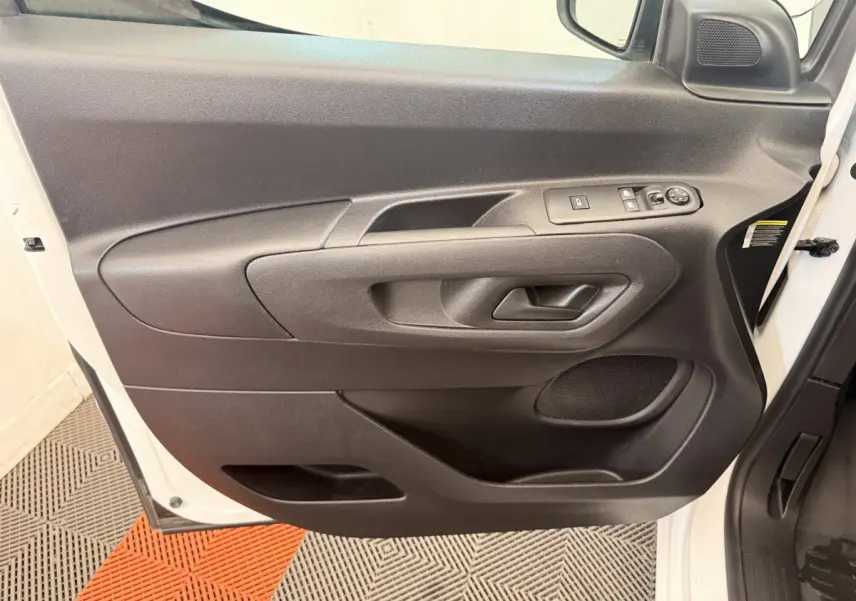 Vue rapprochée de la porte avant gauche noire du Citroën Berlingo blanc, avec commandes de vitres et rétroviseur.