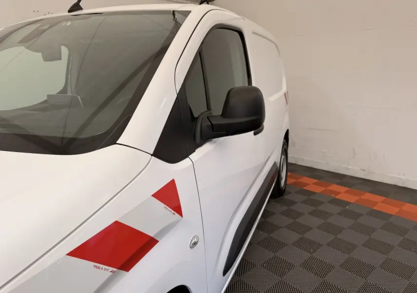 Vue 3/4 avant droit d’un Citroën Berlingo blanc 2019 avec bandes rouges diagonales sur l’aile avant.
