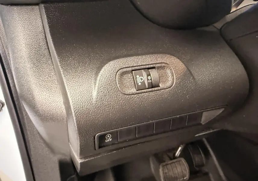 Détail intérieur côté gauche du tableau de bord du Citroën Berlingo blanc 2019, avec commande de réglage des phares.