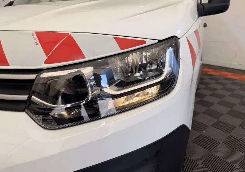 Gros plan sur l'avant droit blanc d'un Citroën Berlingo 2019 avec bandes rouges réfléchissantes sur le capot et la porte.