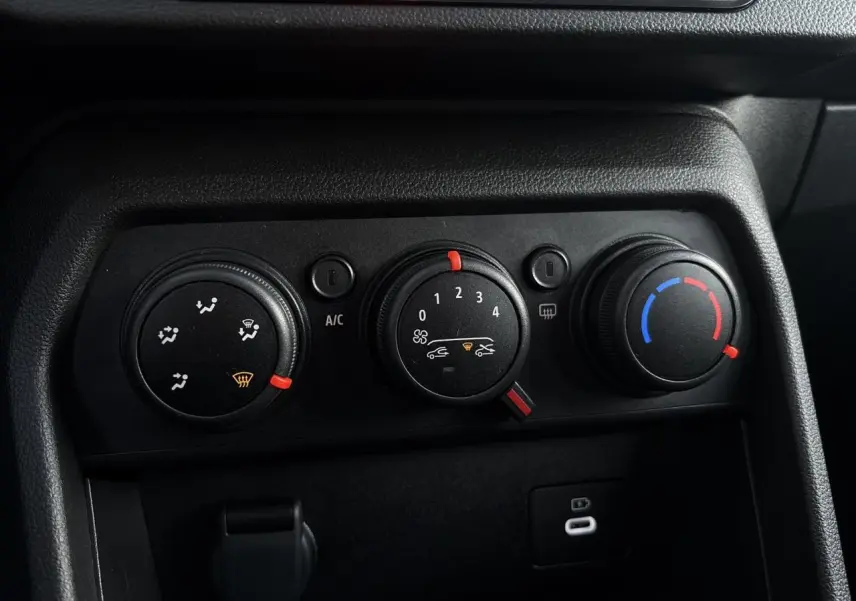 Gros plan sur les commandes de climatisation manuelle noires du tableau de bord de la Dacia Sandero Stepway 2025.