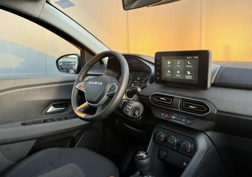 Intérieur avant droit du Dacia Sandero Stepway 2025, volant multifonction et écran tactile multimédia visible.