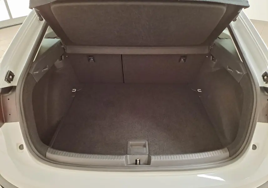 Coffre ouvert vu de l'arrière d'un Volkswagen Taigo blanc pur 2024, espace de chargement vide et tapis noir.