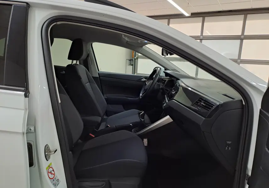 Vue intérieure côté conducteur du Volkswagen Taigo blanc pur 2024, montrant sièges noirs et tableau de bord moderne.