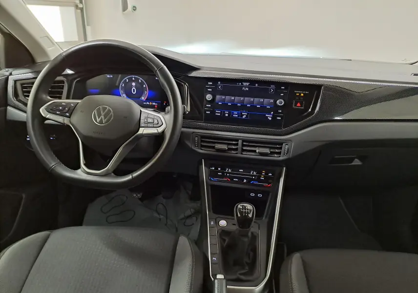 Vue intérieure avant du Volkswagen Taigo 2024 avec volant multifonction, écran tactile et levier de vitesses manuel.