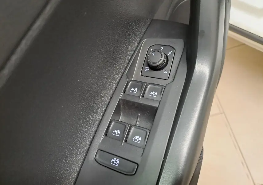 Gros plan sur les commandes de lève-vitres et réglage des rétroviseurs côté conducteur du Volkswagen Taigo blanc 2024.