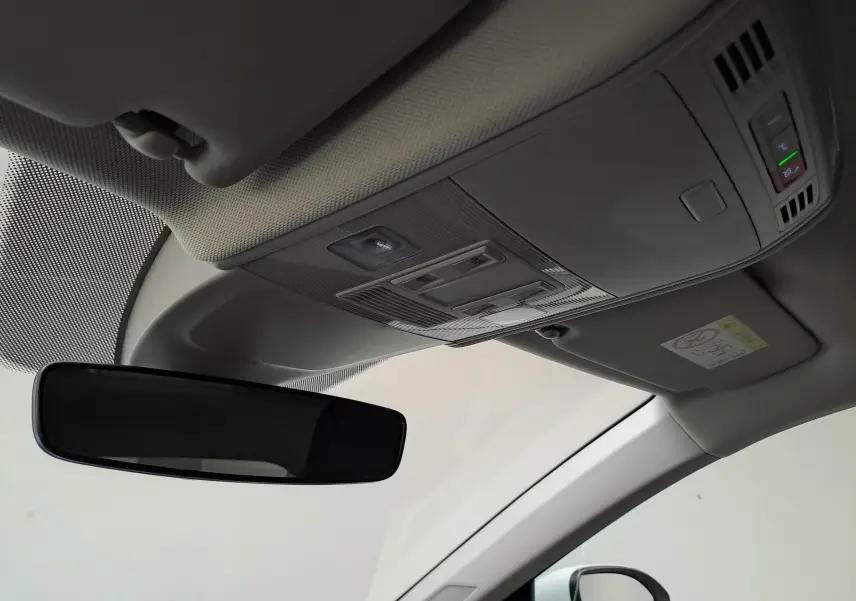 Vue intérieure du plafond avant du Volkswagen Taigo blanc, avec rétroviseur et commandes d'éclairage intégrées.