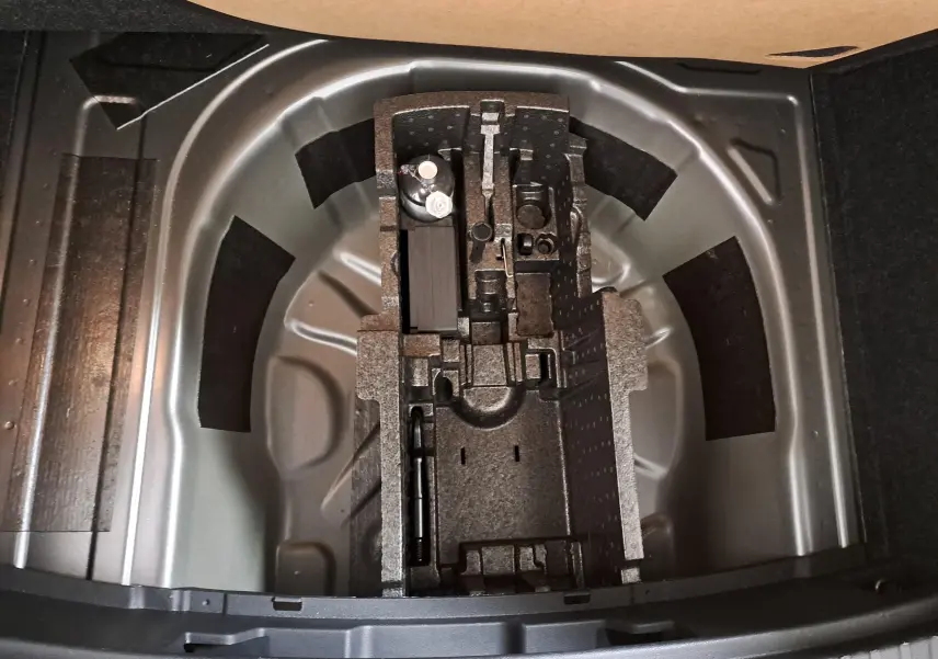 Coffre ouvert d'une Skoda Scala gris graphite, vue plongeante sur le rangement pour roue de secours et outils.