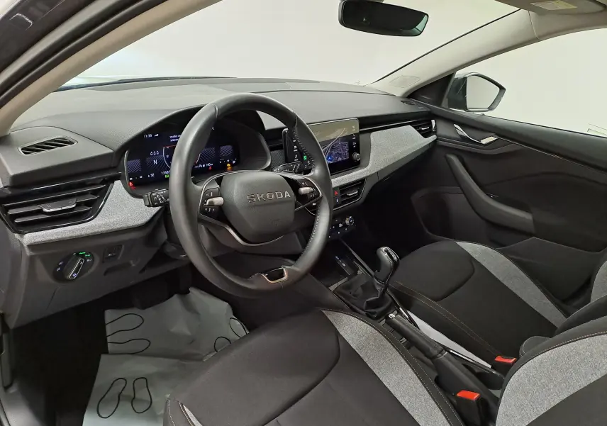 Vue intérieure côté conducteur du Skoda Scala 2025, montrant le volant, tableau de bord numérique et sellerie bicolore noire et grise.