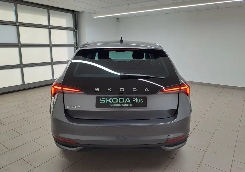 Vue arrière d'une Skoda Scala 2025 gris graphite avec feux allumés et caméra de recul visible en intérieur.