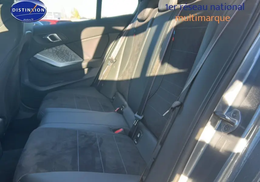 Vue latérale droite de l’arrière intérieur de la BMW Série 1 118da 2025 avec sièges en alcantara noir et coutures bleues.