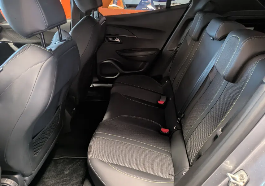 Vue intérieure côté droit des sièges arrière noirs avec surpiqûres vertes du Peugeot 2008 Hybrid 145 e-DCS6 GT 2025.
